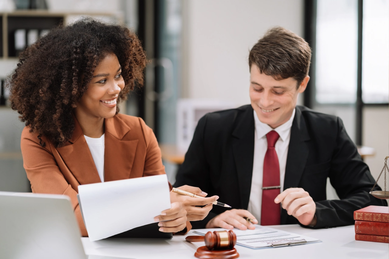 A man and woman sitting at a table with papers.