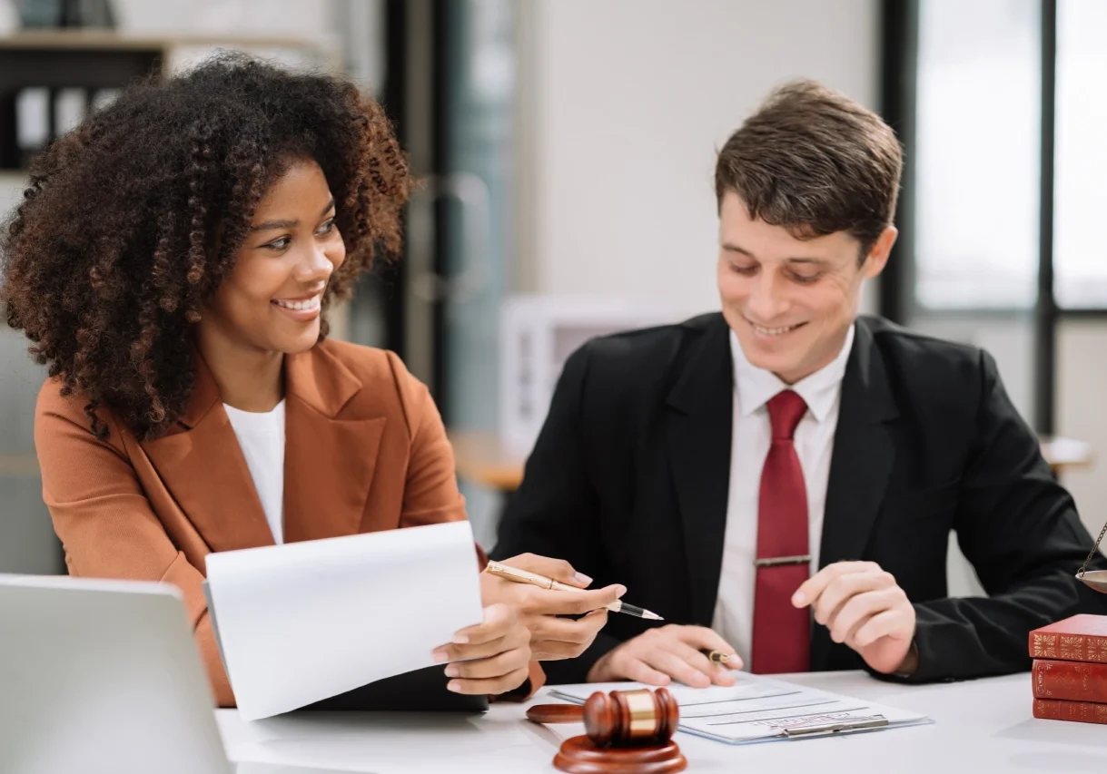 A man and woman sitting at a table with papers.